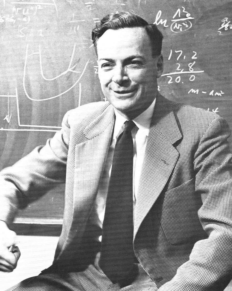Richard Feynman seated at a blackboard covered in equations, 1959